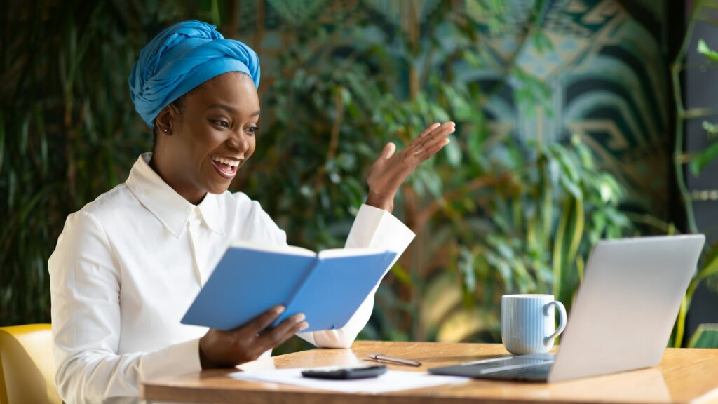 Cheerful young african woman attending online business meeting, cafe interior